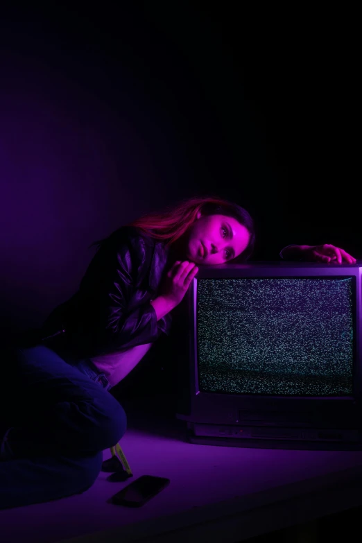 a woman crouching next to a television set
