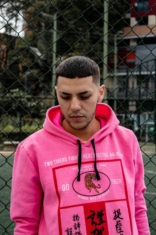 a man in a pink sweatshirt looking at his phone