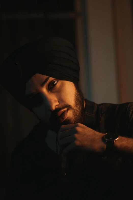 a man is brushing his beard and wearing a black hat