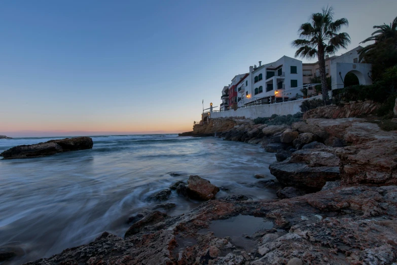 a beach and city by the sea under a sunset sky