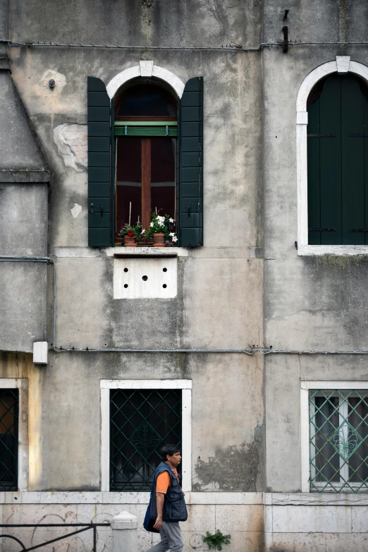 the back end of a person walking past a tall building with two windows