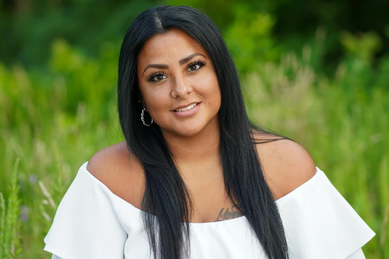 a woman sitting in the grass smiling at the camera