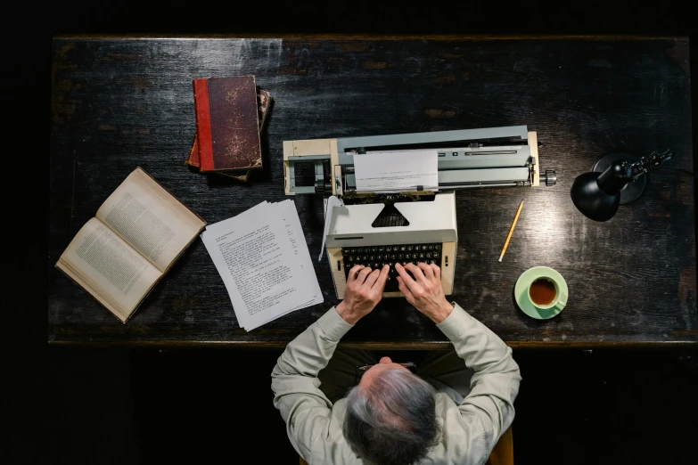 an overhead view of a man typing on a vintage typewriter