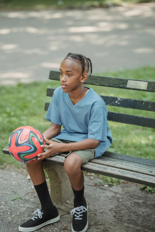 a young child sitting on a bench with a soccer ball