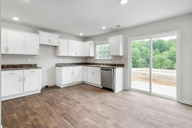 an empty house with wood floors and white cabinets