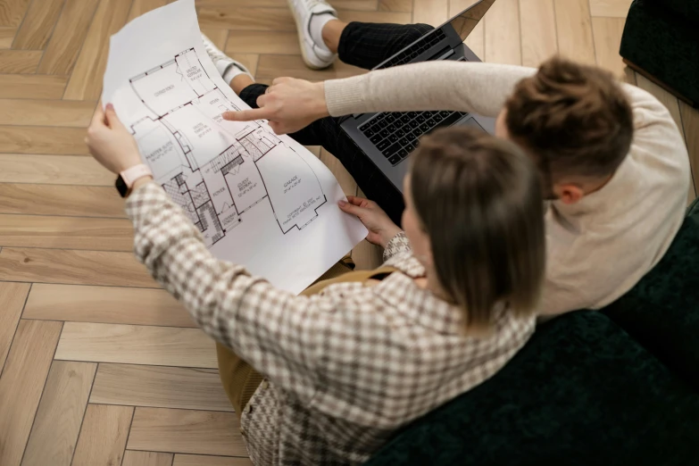 a couple looking over a drawing that is on the floor