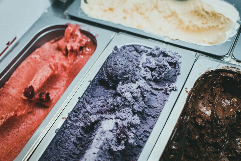 four different colored ice creams in pans sitting next to each other