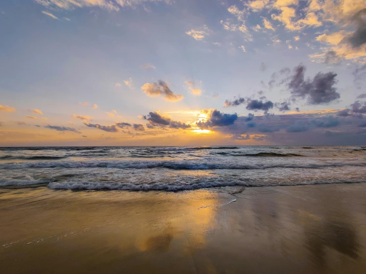 the sun is setting over the ocean on the beach