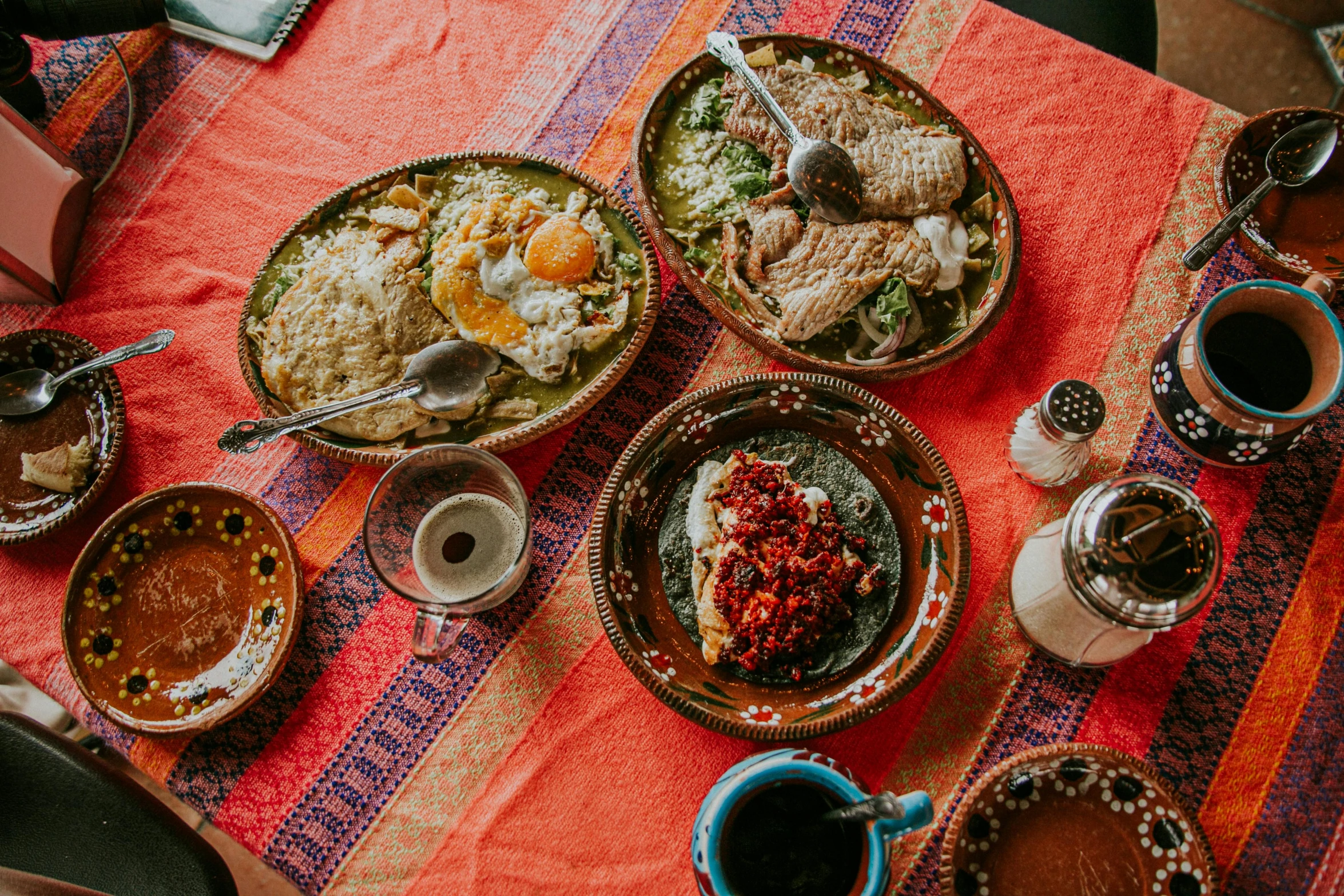 several bowls filled with food on top of a colorful cloth