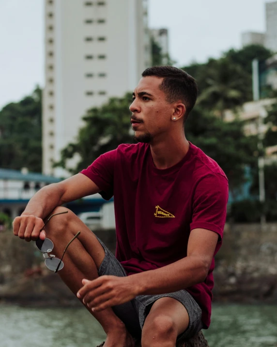 a man in a red shirt sitting down by the water