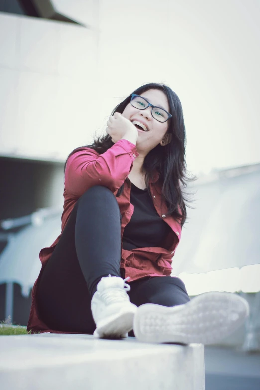 a woman is sitting down wearing a red sweater