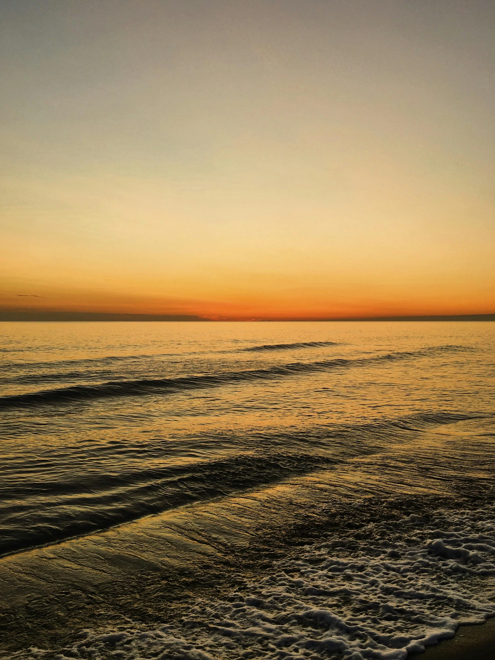 the sun is setting behind a beach with small waves