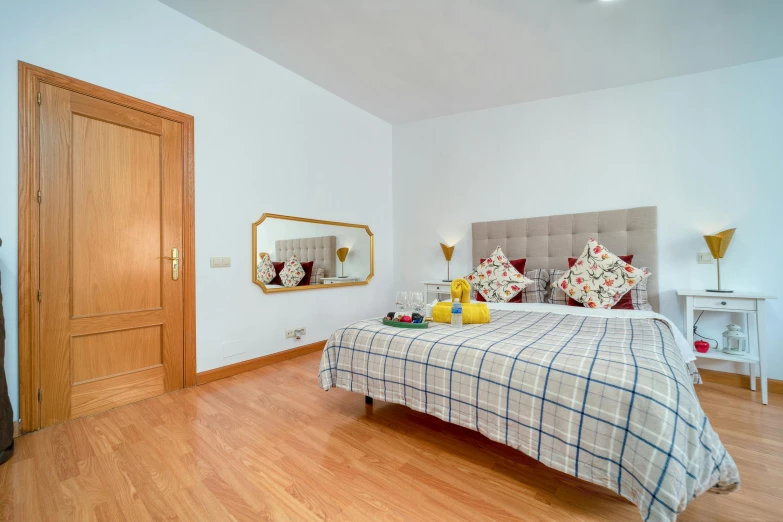 a bed with white and gray comforter on it next to a wooden door