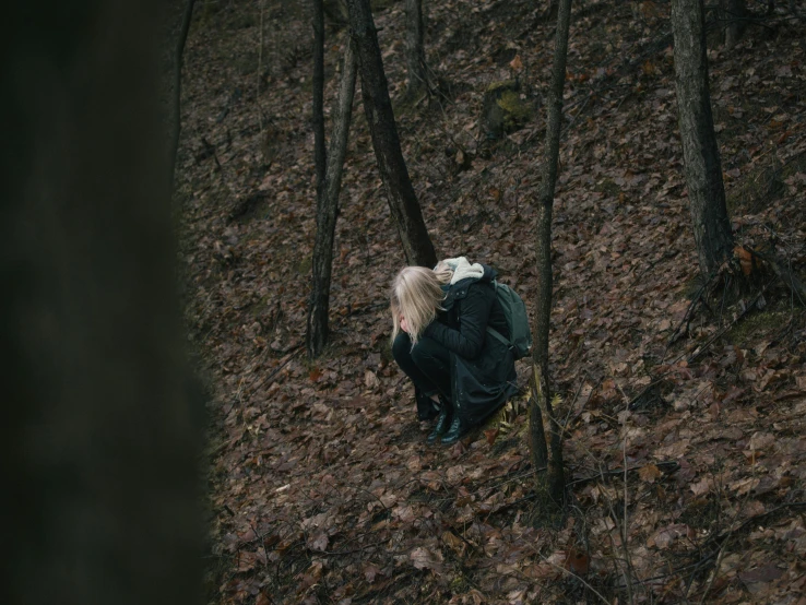 a man in a black jacket is walking through the woods