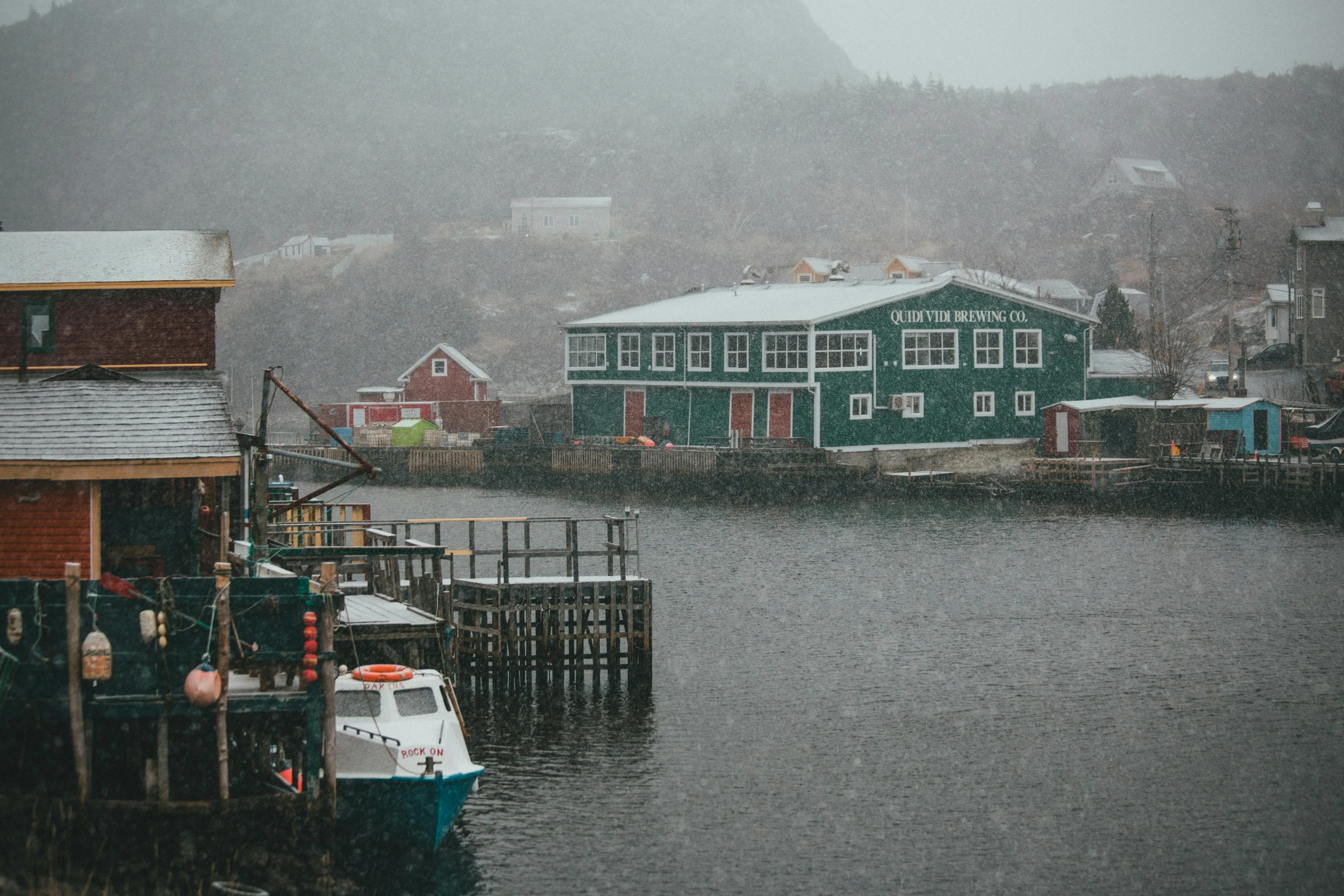 boats sit in the water near homes in the rain