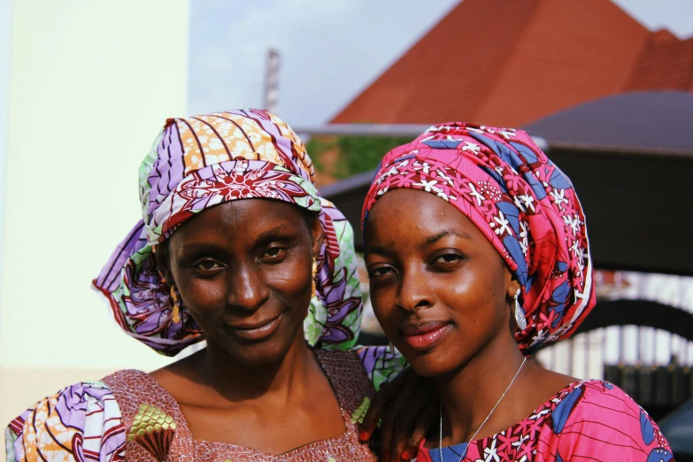 two women pose for the camera while wearing colorful head coverings