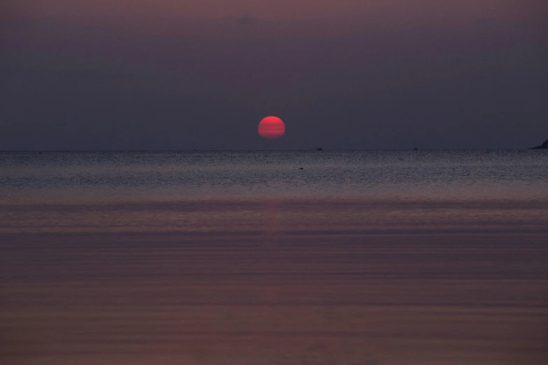 the sun is setting over the ocean on a cloudy day