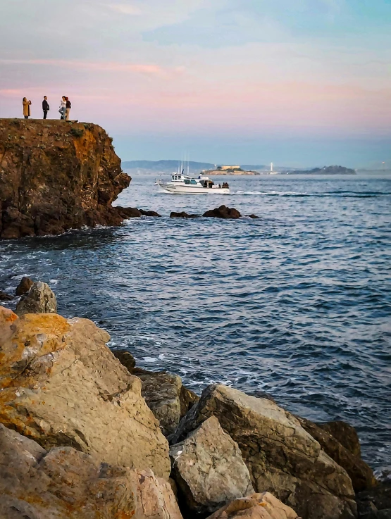 the group of people are standing on rocks near the water