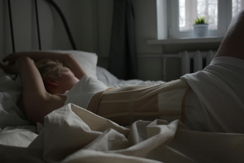 a woman laying on a bed under a blanket