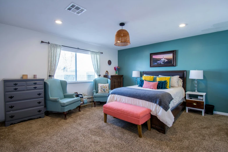 a bedroom with a very colorful bed, chair, nightstand and a big window