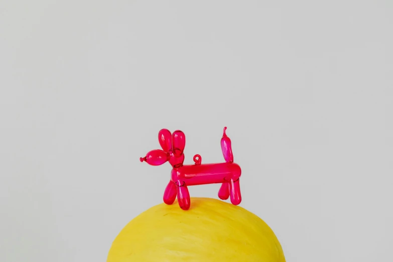 a red dog sitting on top of a yellow ball