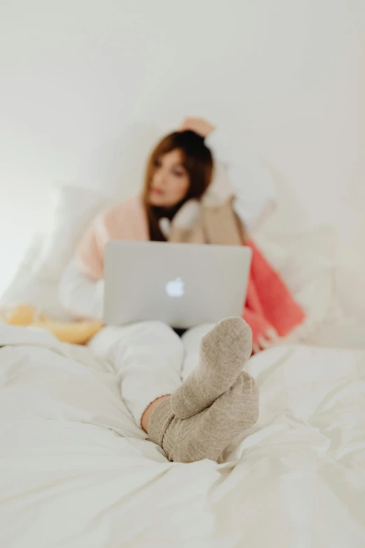 a woman on a bed with her feet propped up to a lap top