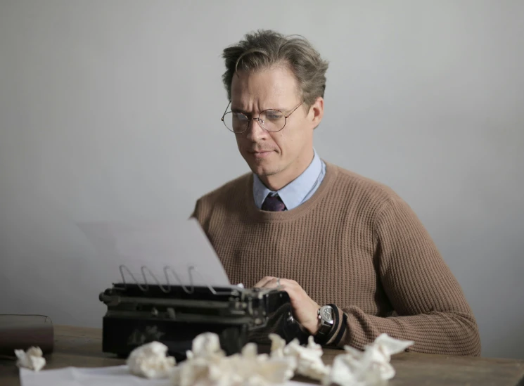 an old man wearing glasses is typing on a typewriter