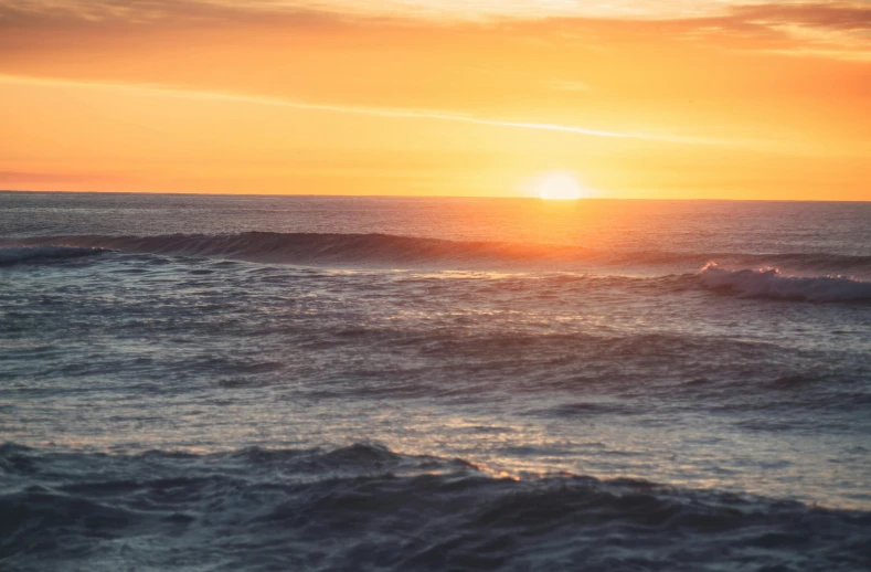 a sun setting over a body of water with waves