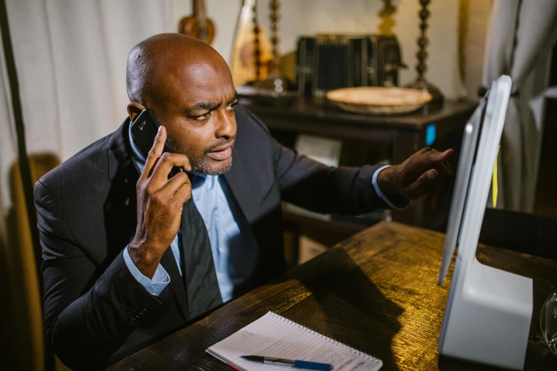 a man is sitting at a desk while talking on the phone