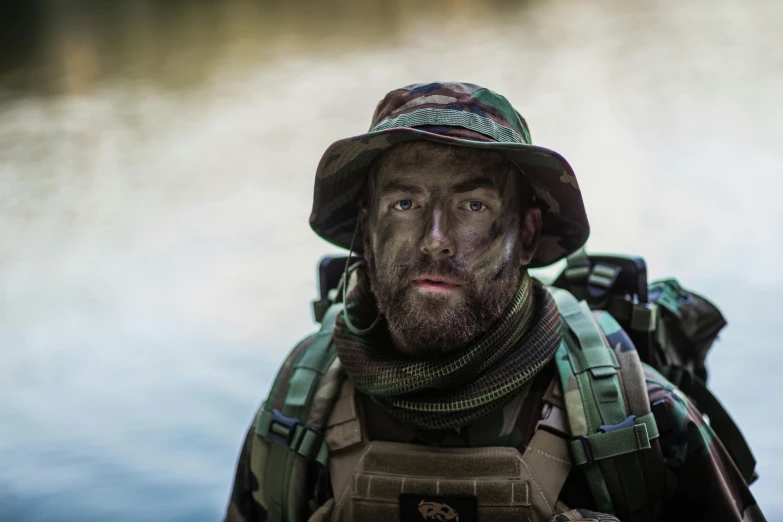 a man with a beard wearing a hat and camouflage gear