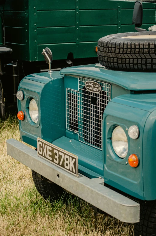 an old blue land rover with four tires sitting in the grass