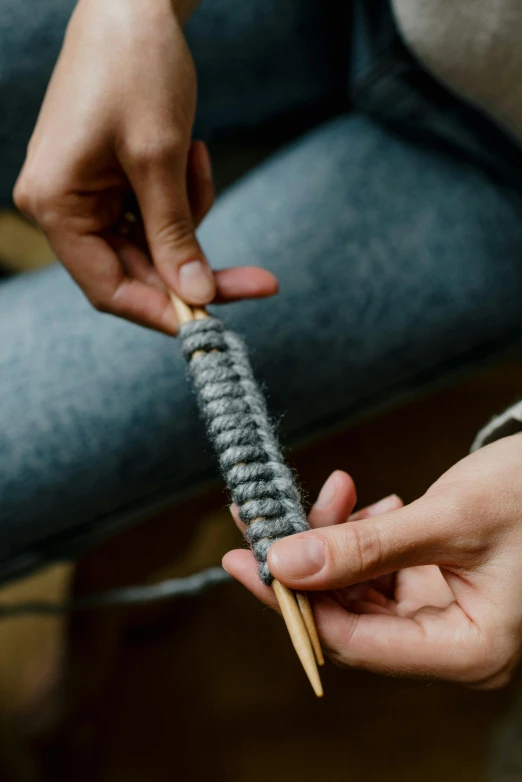 a woman holding onto a wooden knitting needles