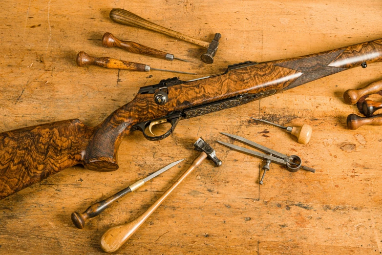 guns and some hammers on a table with wood background