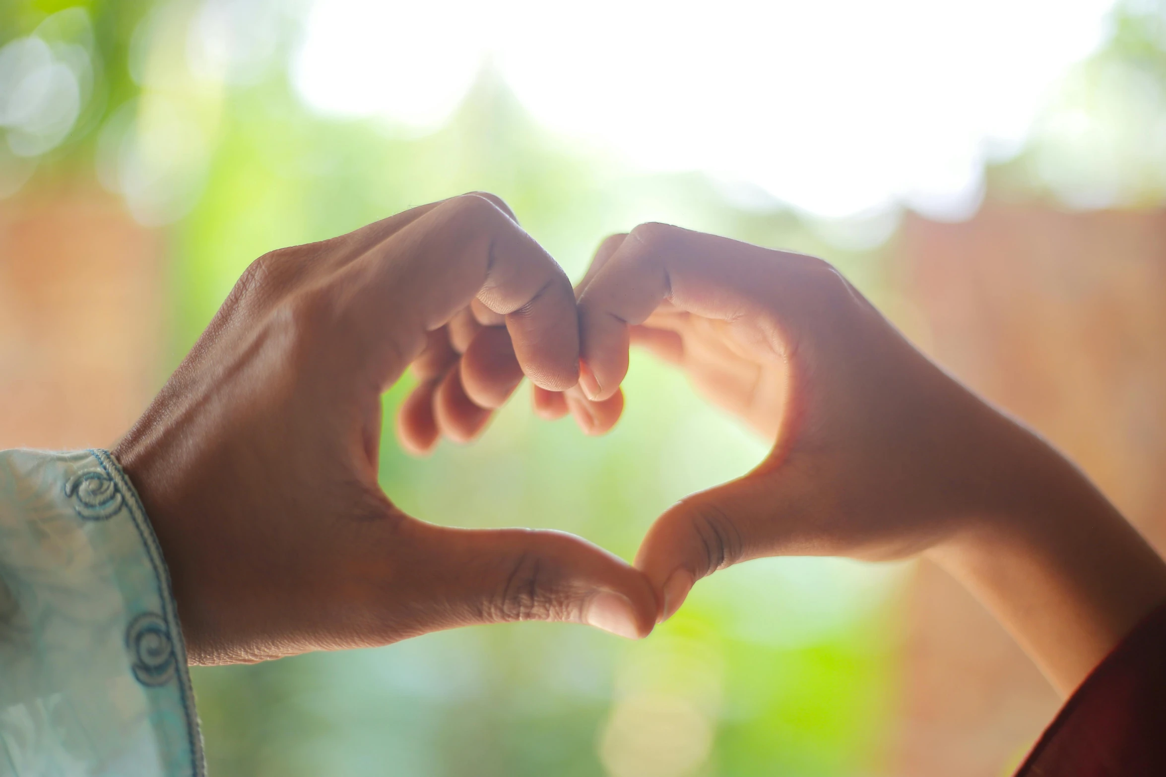 two hands are making a heart shape with their fingers