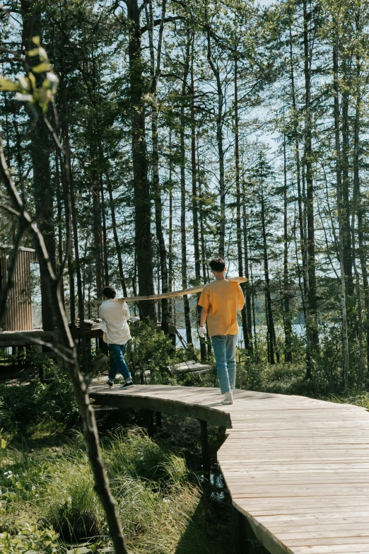 two boys walking across a wooden walkway in the woods