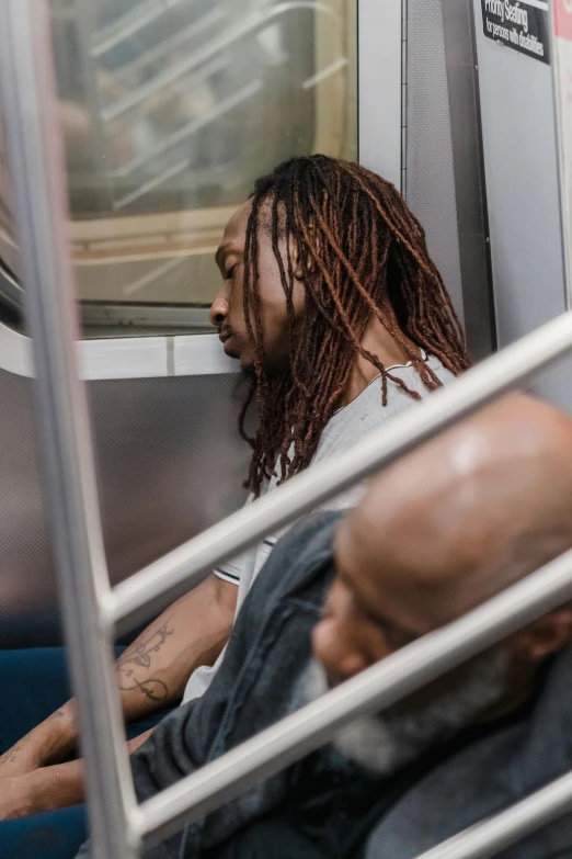 a man in a gray top sitting on the subway train