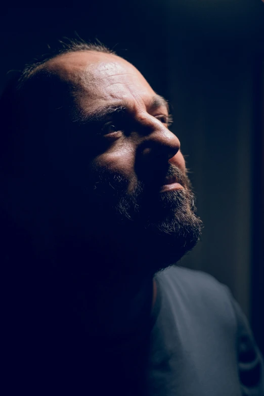 a bearded man standing in a dark room