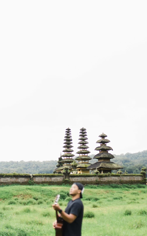 a man standing in a field with some tall buildings behind him