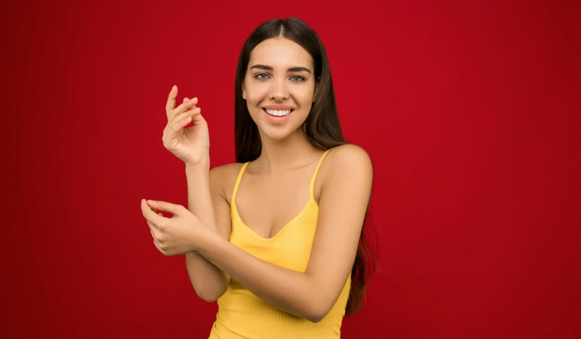 a woman in yellow posing on a red background