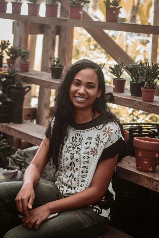 a woman sitting on the ground near some potted plants