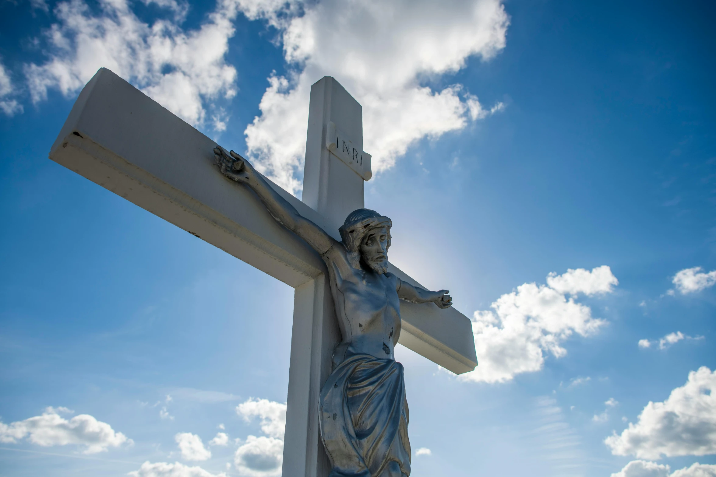 a large white cross with a statue on the top