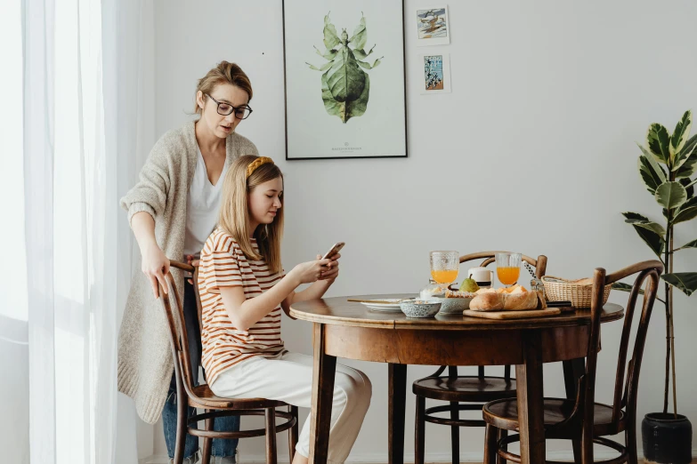 a mother and daughter sitting at the table