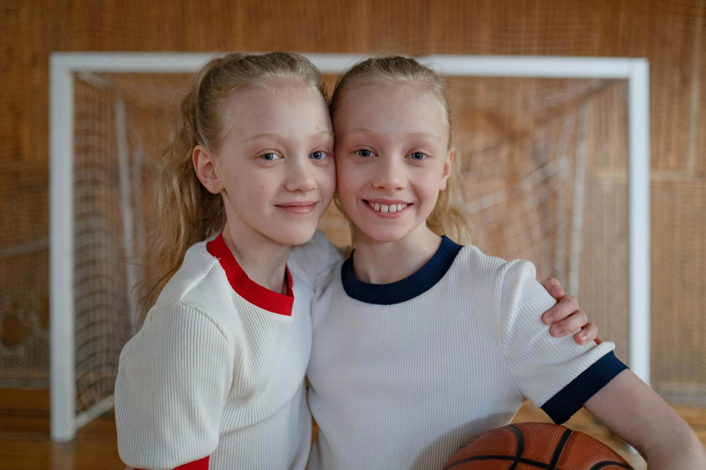 two s standing next to each other holding a basketball