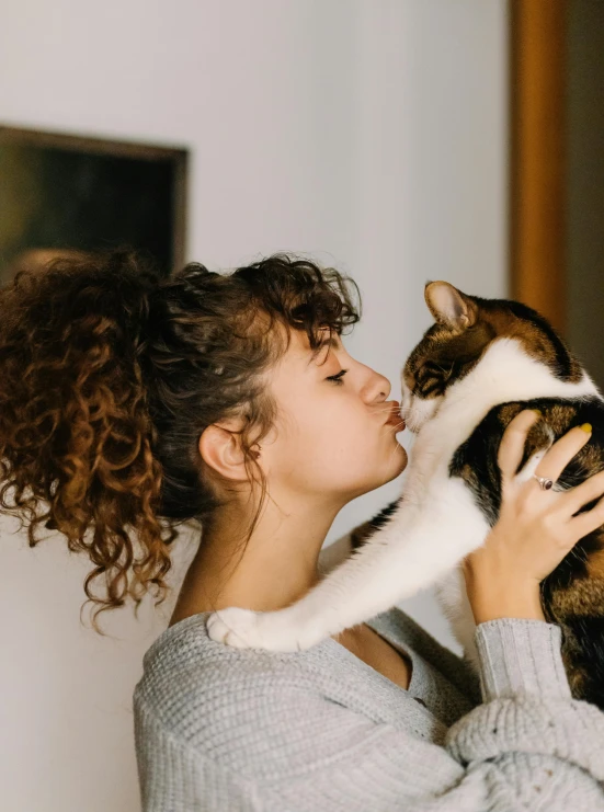 a woman kissing a brown and white cat