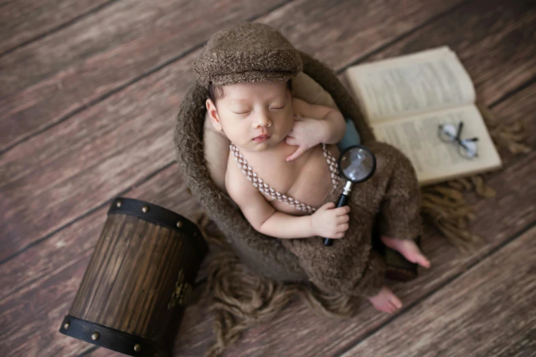 a baby in a brown blanket holding a magnifying glass