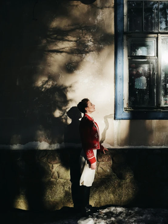 a woman is standing by a building by some windows