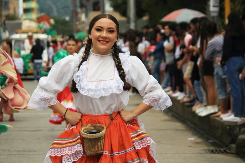 a woman in a mexican folk dress stands on the side walk