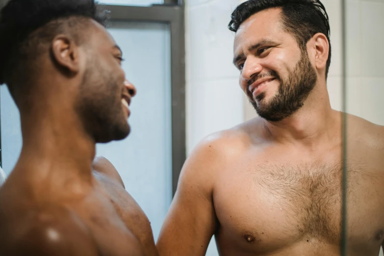 two men are smiling while they look in the mirror