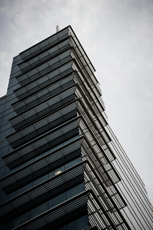 a skyscr with very tall windows in front of cloudy sky