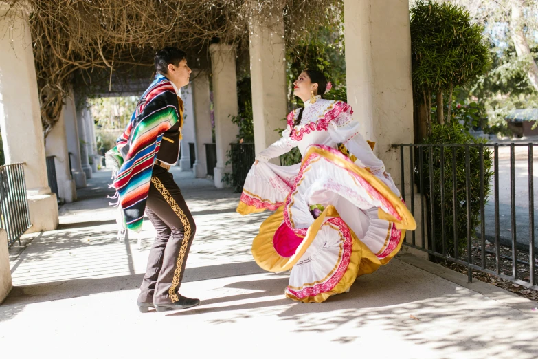 two people dressed in asian attire next to a fence